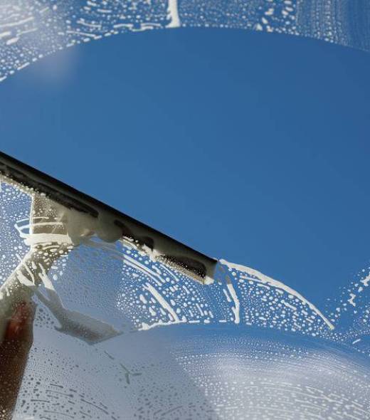 Clear blue sky Window cleaner using a squeegee to wash a window