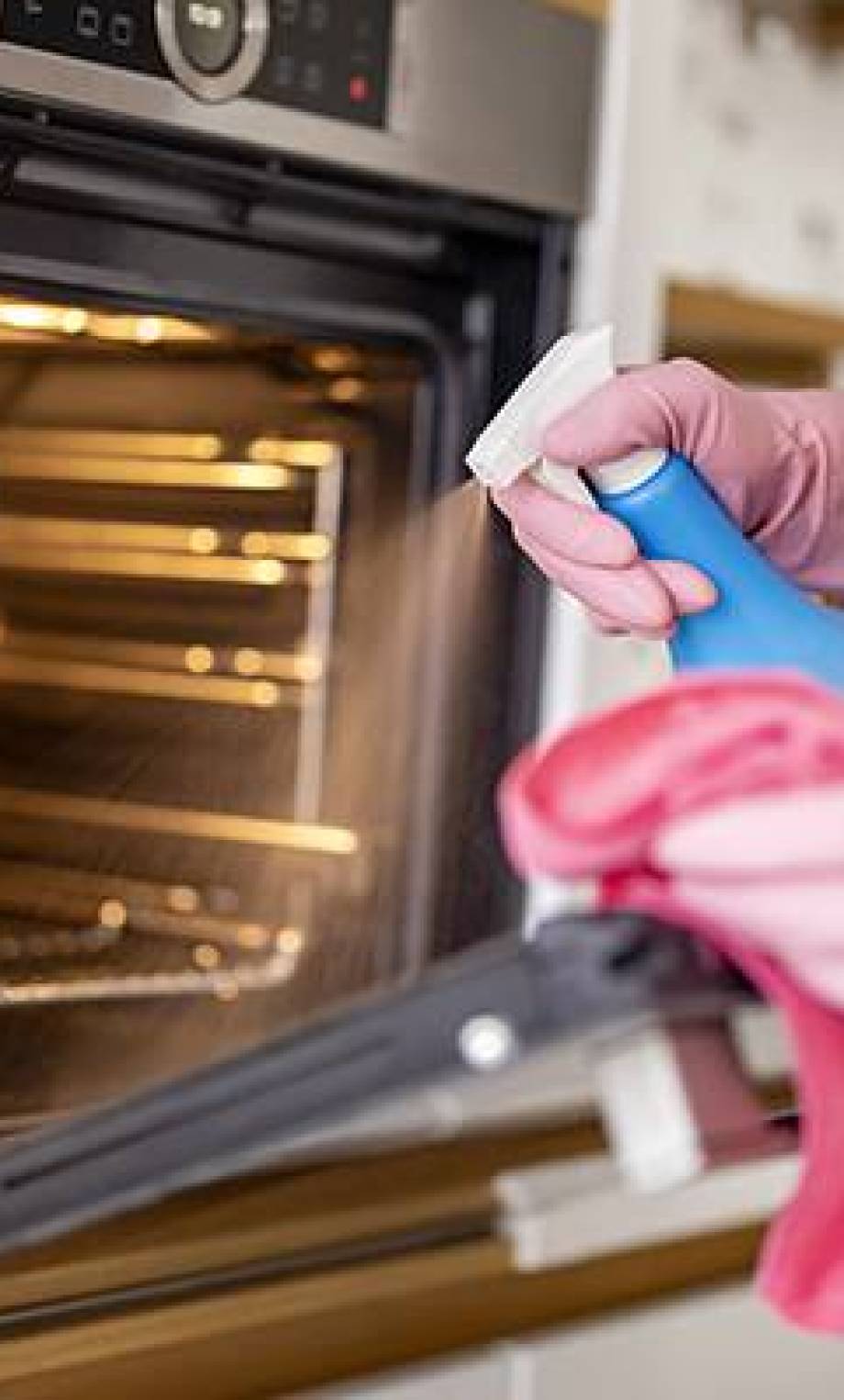 Young woman cleaning oven with rag in kitchen Young woman cleaning oven with rag in kitchen.Woman cleaning oven in kitchen.